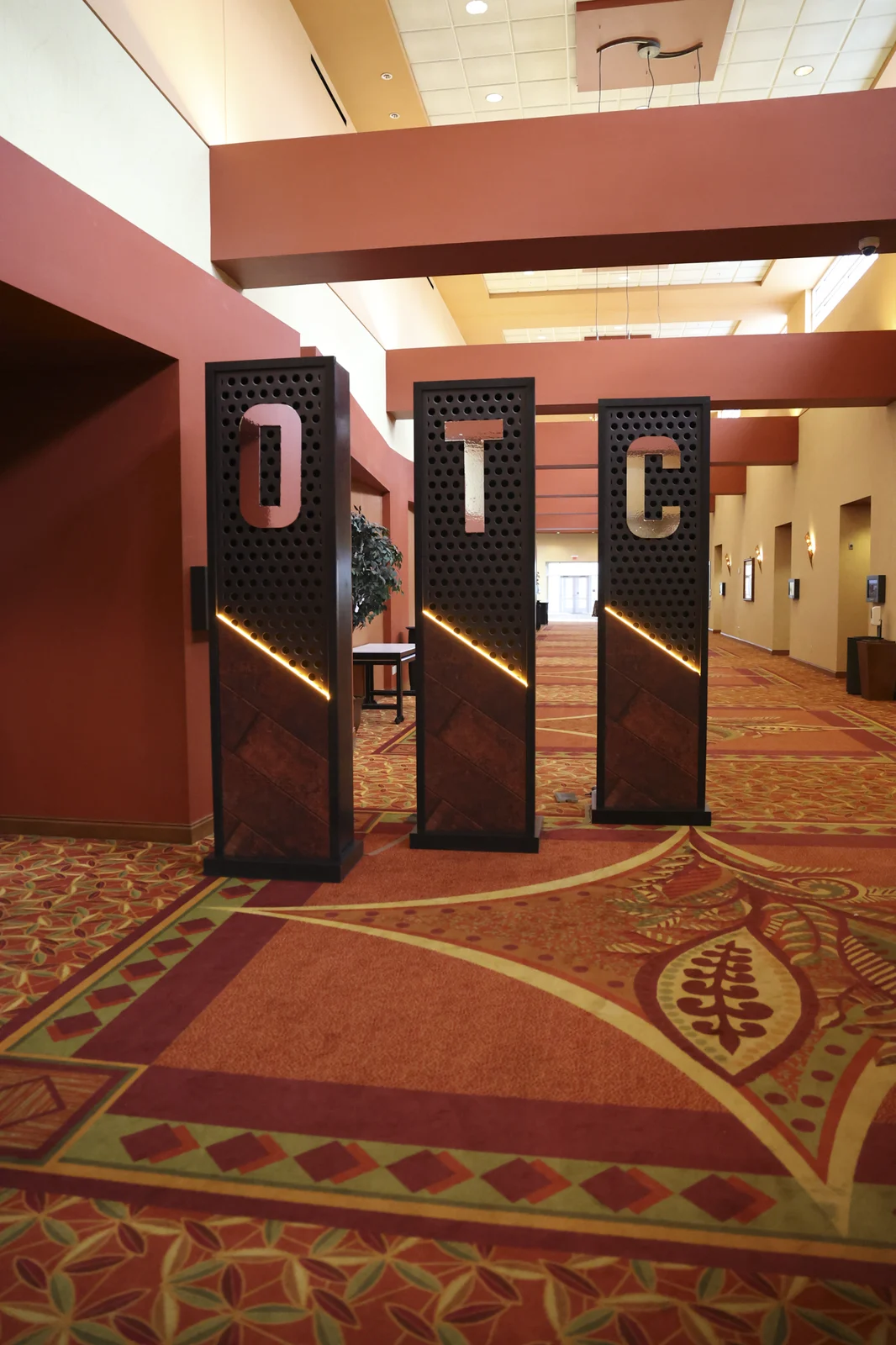 Three printed pillars spelling O T C lining the entrance hallway