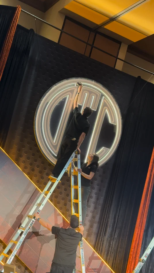 Jack on a ladder cleaning the illuminated OTC sign after installing it