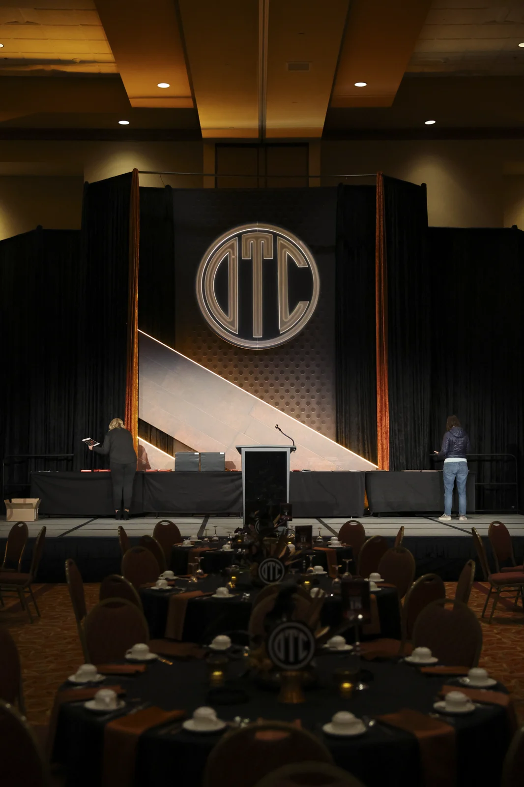 The illuminated OTC monogram above the stage with the podium below