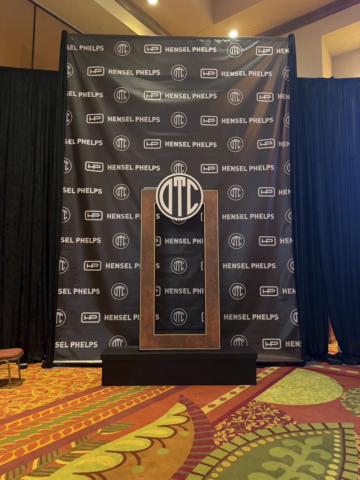 The step-and-repeat backdrop with a podium in front of it