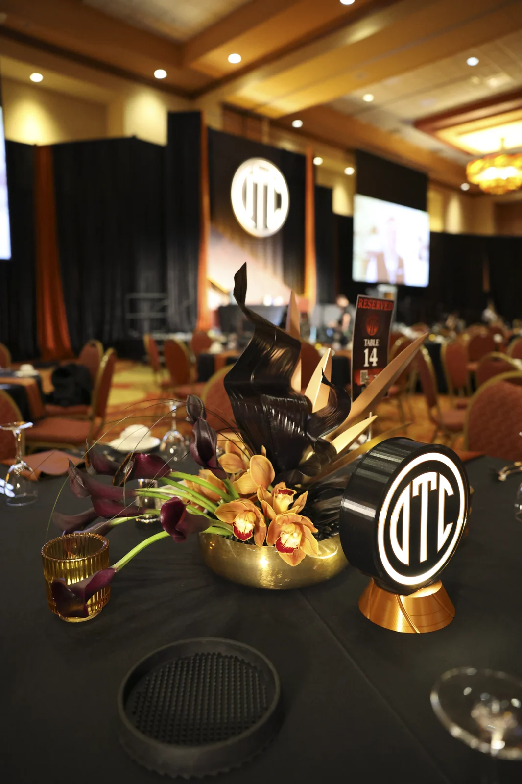Banquet table with an OTC table sign, amber florals, and candlelight