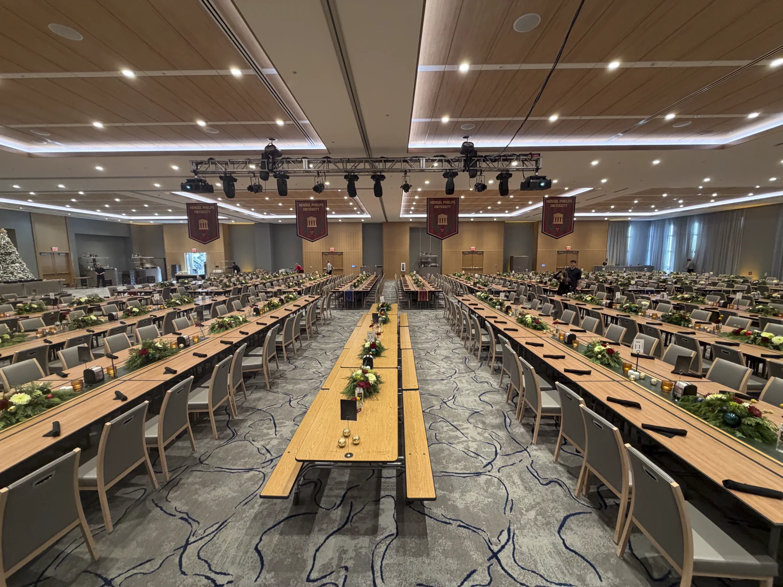 Main ballroom set with long banquet tables, printed runners, and greenery