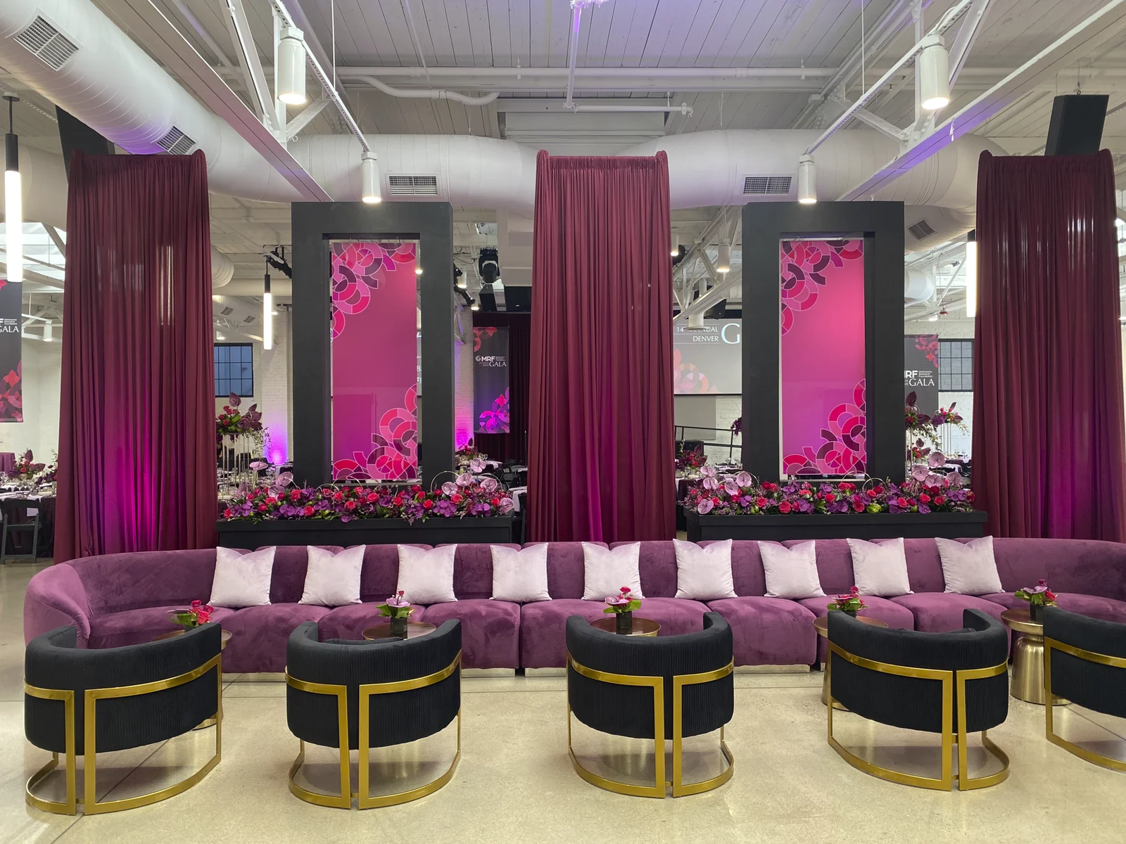 Gala lounge with tall printed plexiglass panels in black frames behind a plum velvet banquette