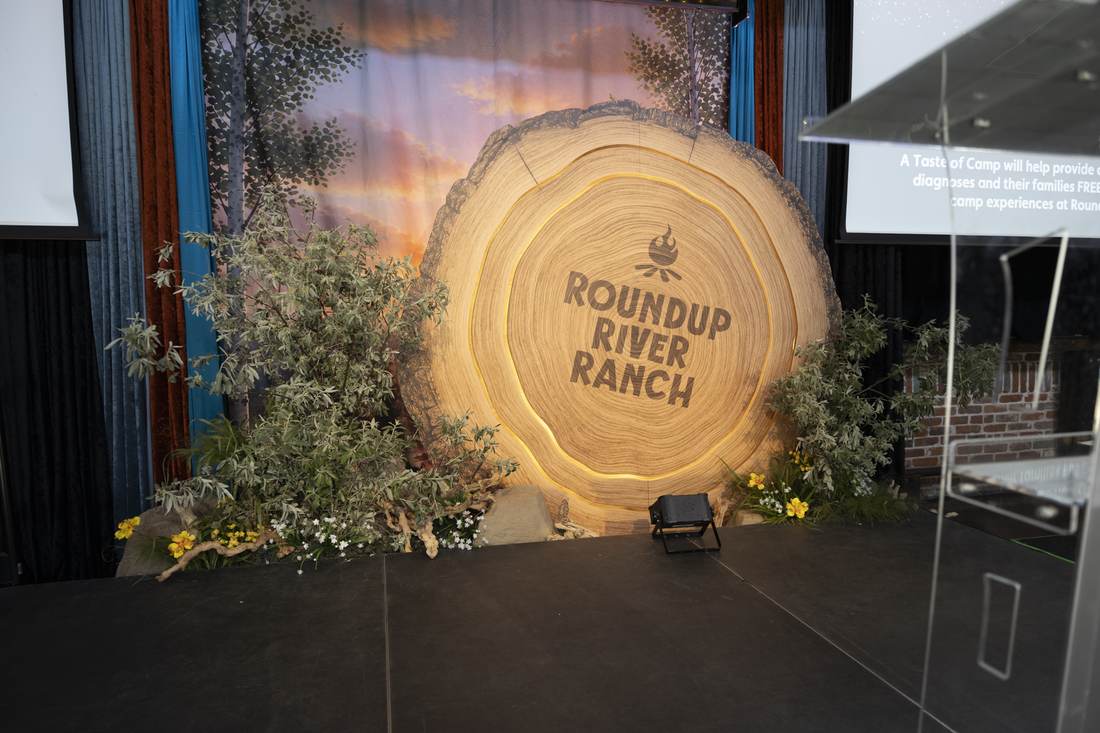 Tree-stump cross-section stage backdrop with Roundup River Ranch logo, illuminated rings