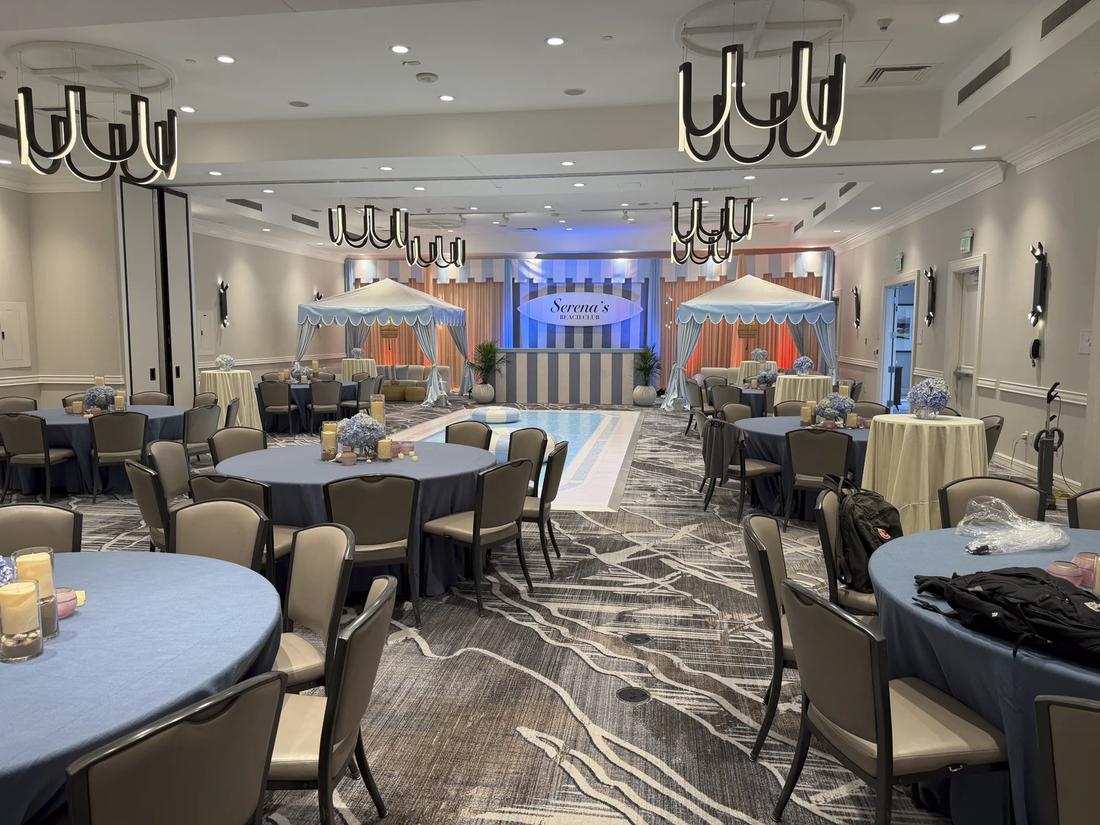 The ballroom during the event with blue lighting and guests' tables