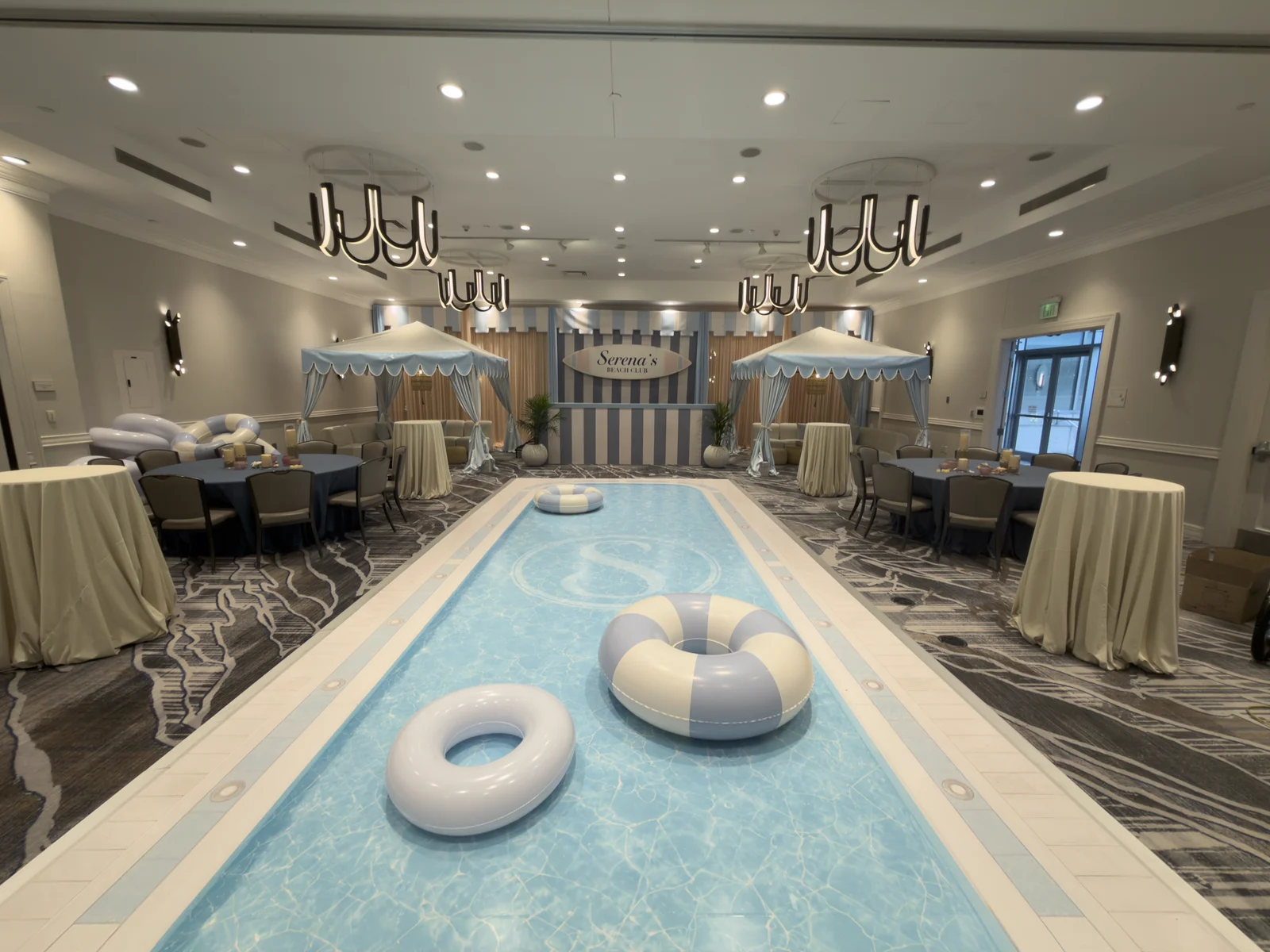 Wide view of the ballroom showing the pool dance floor, cabanas, and bar backdrop