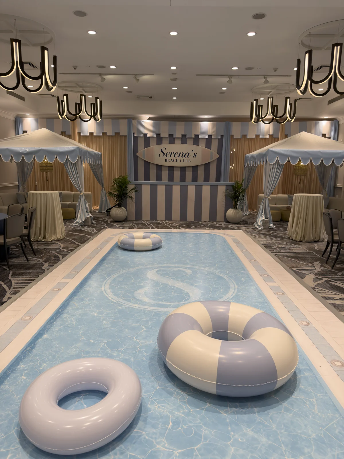 Printed pool dance floor with the S monogram, looking toward the bar backdrop and cabanas